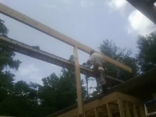 Carpenter setting a ridge beam over a new addition frame — Ice Dam Removal by Roofing Brothers in Levittown