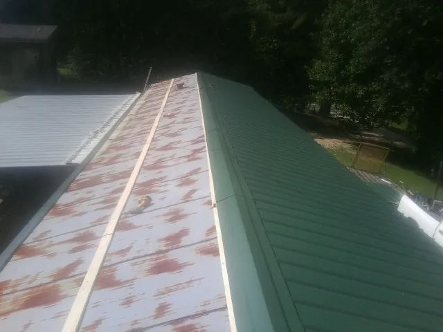 Old rusted panels beside newly installed green metal roofing — Wind Damage Roof Repair by Roofing Brothers in Levittown