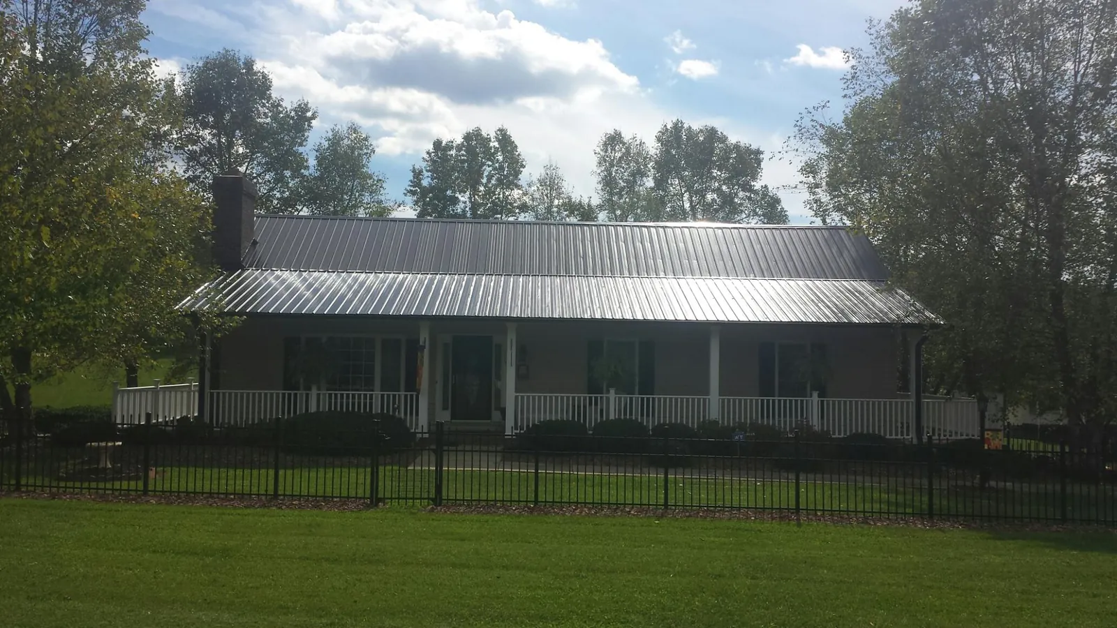Gray metal roof on a brick ranch with a full width front porch — Gutter Guard Installation work by our crew in Levittown