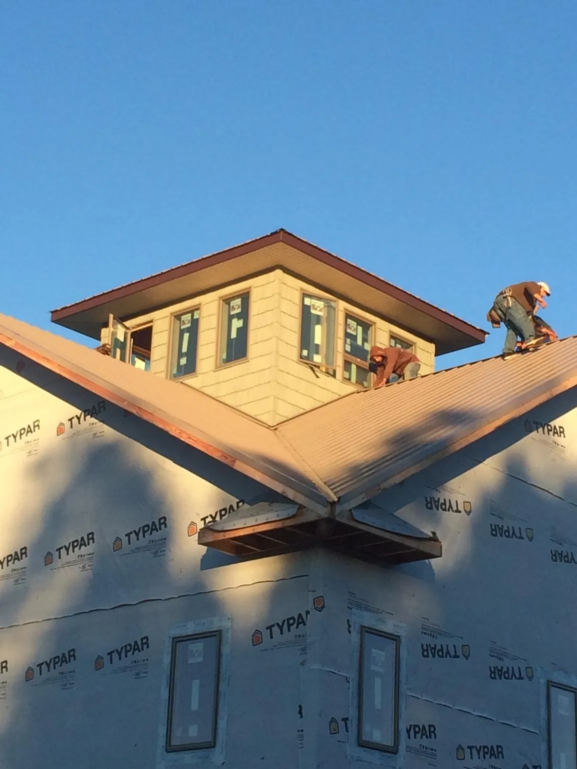 Roofers working around a rooftop cupola on a new metal roof at sunset — Roof Waterproofing in Levittown by Roofing Brothers